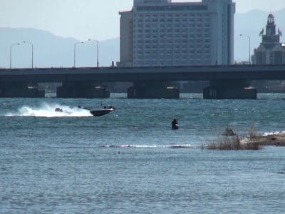 真野川河口の立ち込み釣りと沖を通過中のバスボート。月曜日の琵琶湖は南寄りの強風で大荒れになりました（2月28日11時50分頃）