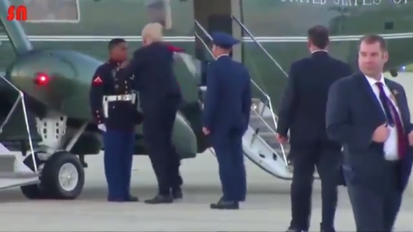 風に飛ばされた若い黒人の海兵隊員の帽子を追いかけて屈んで拾ってかぶせてあげるトランプ大統領しかしまた強風が吹いて帽子が飛ばされる。またもや拾いに行く。